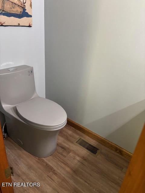 bathroom with toilet, wood finished floors, visible vents, and baseboards