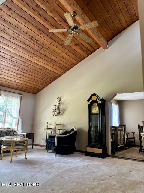 living area featuring ceiling fan, vaulted ceiling with beams, wooden ceiling, carpet flooring, and baseboards