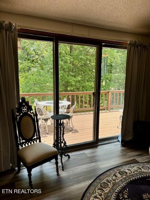 doorway to outside featuring a textured ceiling and wood finished floors