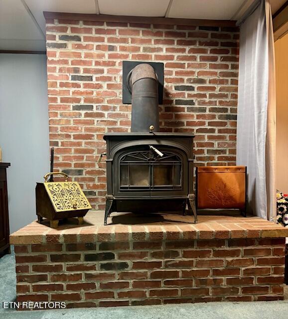 interior details featuring a wood stove, carpet, and a drop ceiling