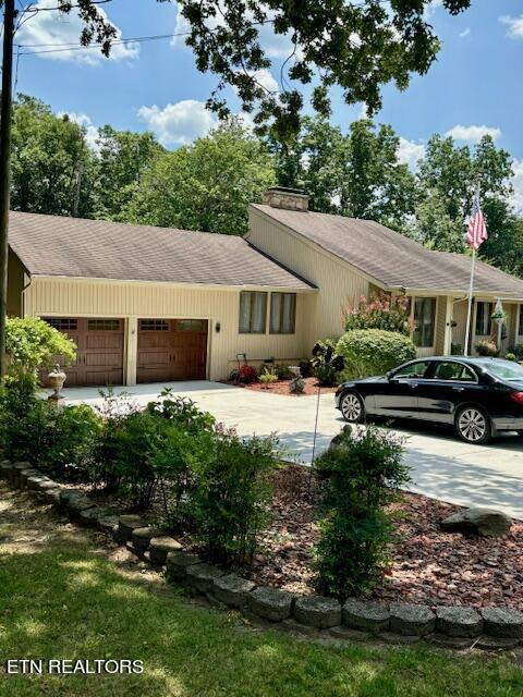 view of front of home with concrete driveway, a chimney, and an attached garage