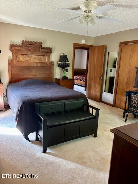 bedroom featuring ceiling fan, a textured ceiling, and light carpet