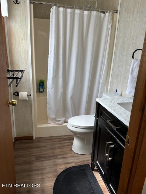 bathroom featuring toilet, a shower with shower curtain, hardwood / wood-style flooring, and vanity