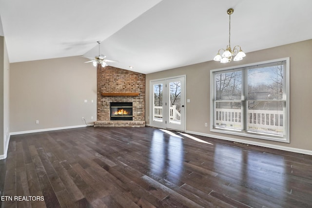 unfurnished living room featuring ceiling fan with notable chandelier, dark hardwood / wood-style floors, vaulted ceiling, and a brick fireplace