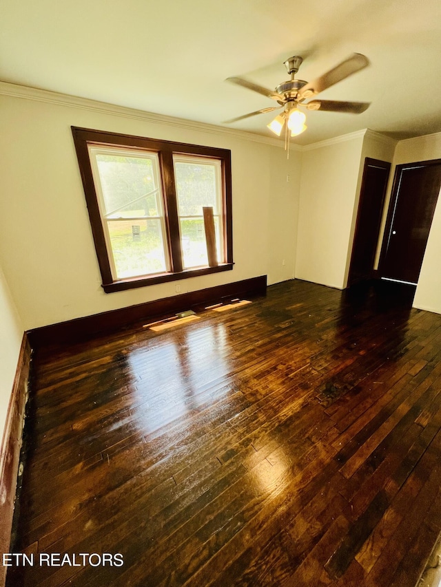 empty room with ceiling fan, dark wood-type flooring, and ornamental molding