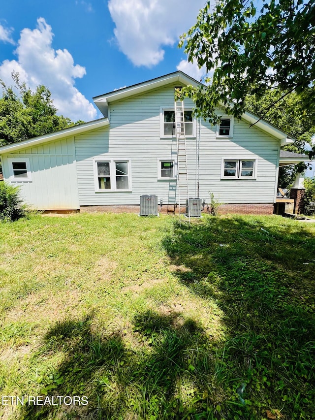 back of property with central AC and a lawn