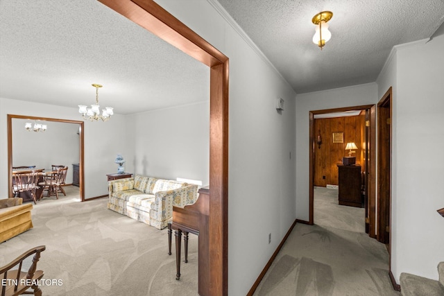 hall featuring ornamental molding, light colored carpet, a textured ceiling, and an inviting chandelier