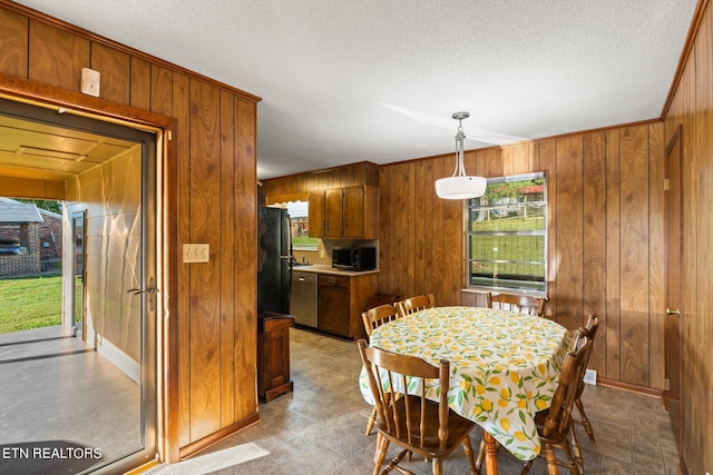 dining area featuring a wealth of natural light, a textured ceiling, and wood walls