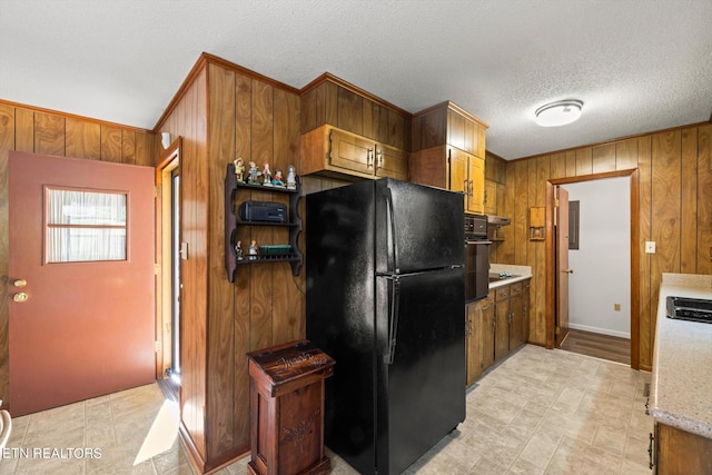 kitchen with black appliances, a textured ceiling, and wood walls