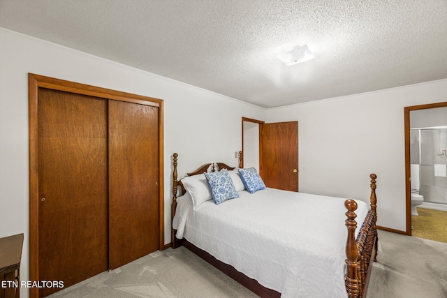 bedroom with connected bathroom, light colored carpet, a closet, and a textured ceiling