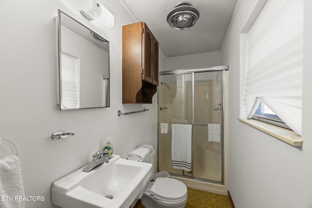 bathroom with toilet, a shower with shower door, sink, and a textured ceiling