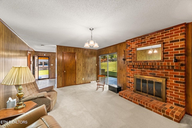 living room with wooden walls, a fireplace, a textured ceiling, light colored carpet, and a chandelier