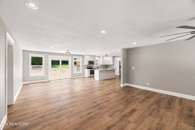 unfurnished living room featuring ceiling fan, sink, and hardwood / wood-style flooring