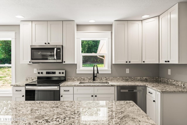 kitchen with sink, white cabinetry, appliances with stainless steel finishes, and a wealth of natural light