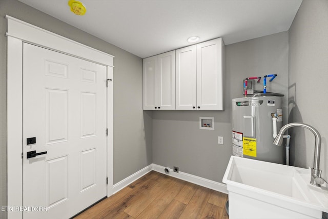 washroom with water heater, cabinets, sink, hookup for a washing machine, and hardwood / wood-style flooring