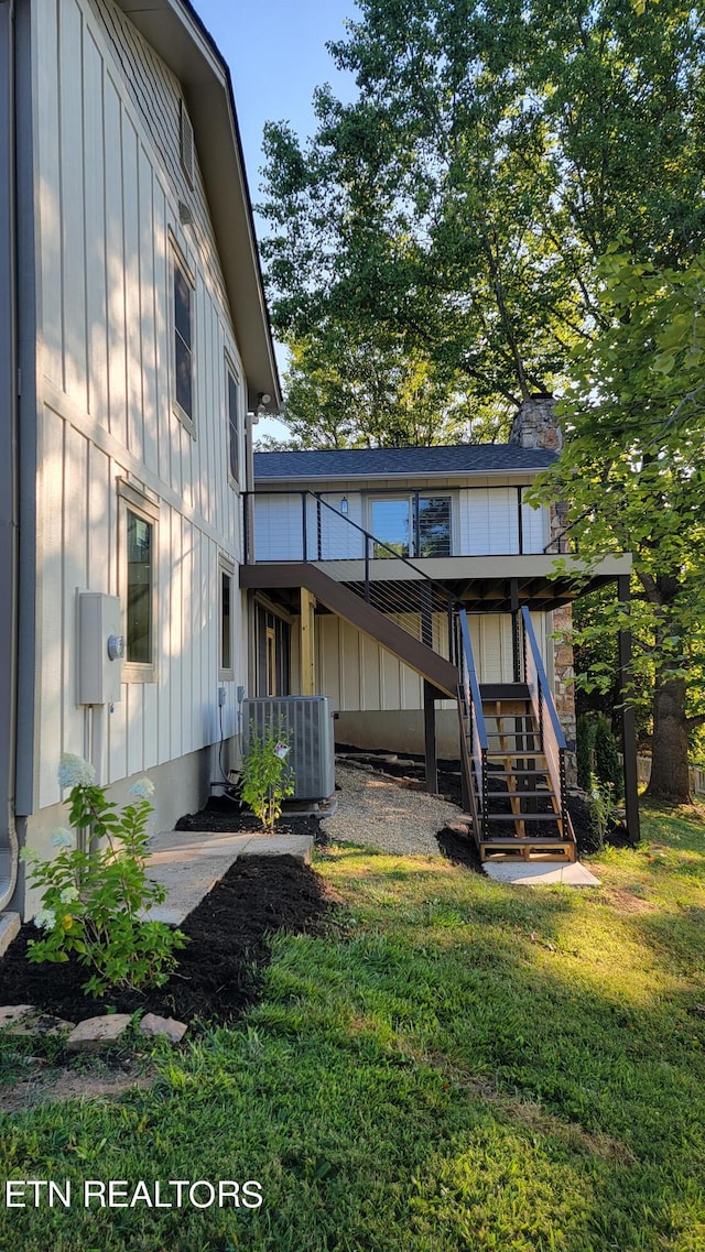 back of property featuring a lawn and central AC