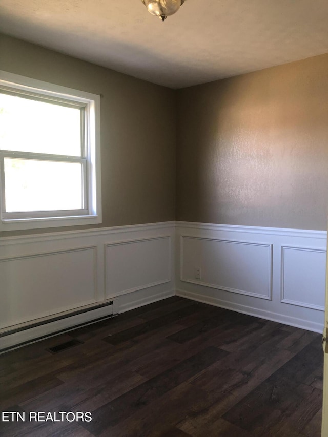 empty room featuring a baseboard radiator and dark wood-type flooring