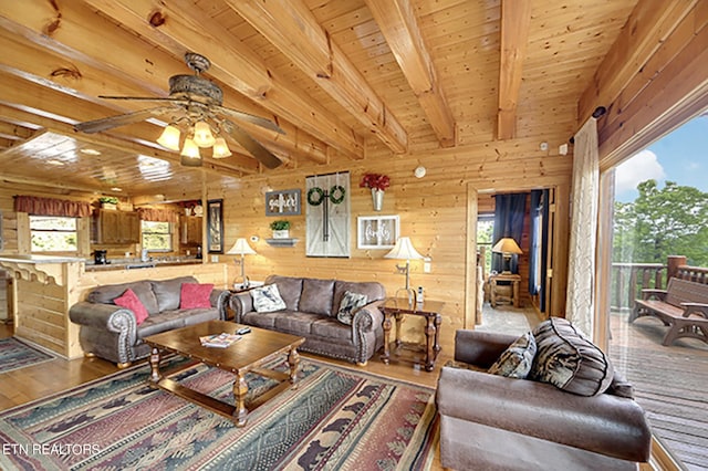 living room with a wealth of natural light, wood walls, beam ceiling, and wooden ceiling