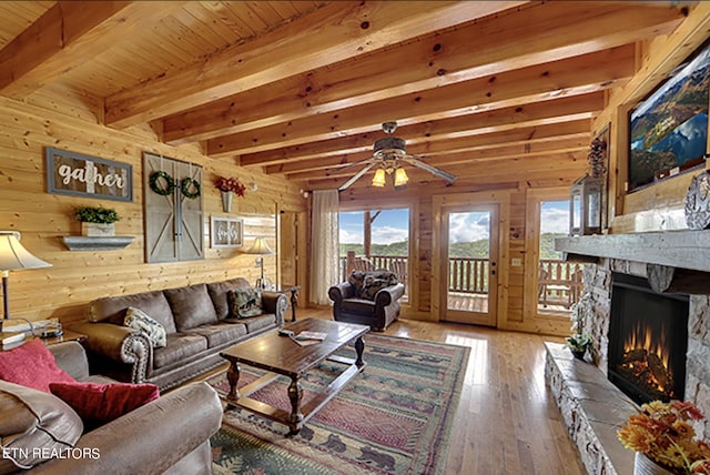 living room featuring a fireplace, wood walls, hardwood / wood-style floors, and beamed ceiling