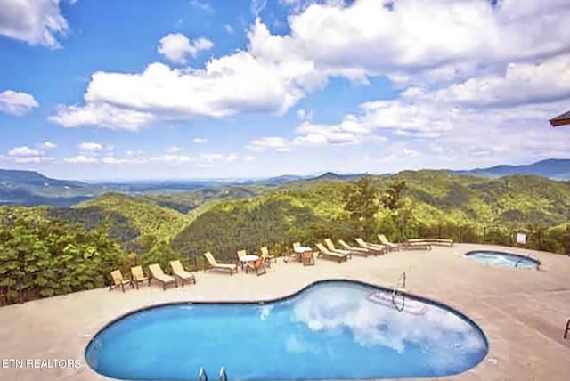 view of swimming pool with a mountain view, a patio, and a hot tub