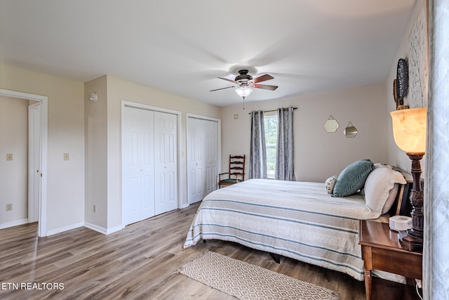 bedroom featuring two closets, hardwood / wood-style floors, and ceiling fan