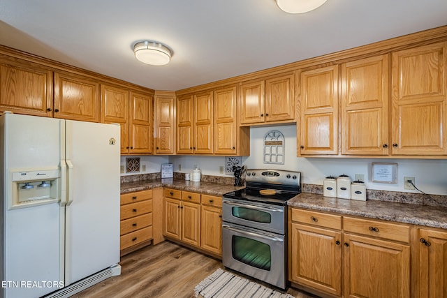 kitchen with light hardwood / wood-style floors, white fridge with ice dispenser, and range with two ovens