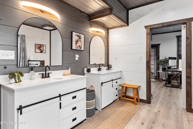 bathroom with wood walls, vanity, and hardwood / wood-style floors