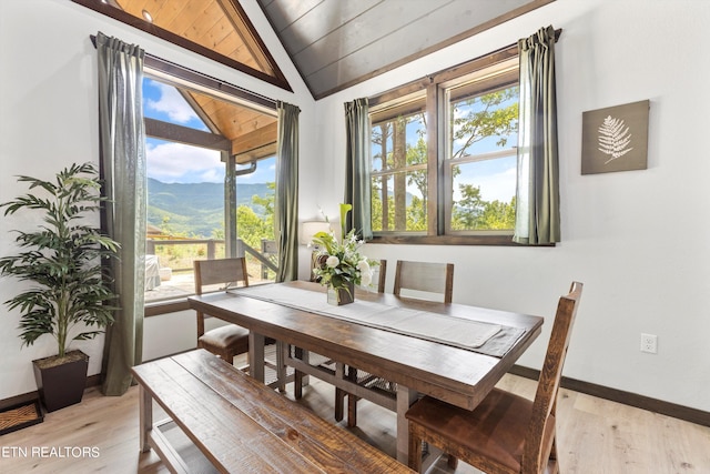 dining area featuring wooden ceiling, vaulted ceiling, light hardwood / wood-style floors, and a mountain view