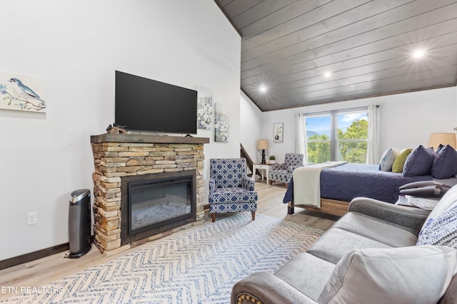 bedroom with wooden ceiling, light wood-type flooring, vaulted ceiling, and a stone fireplace