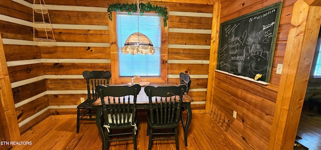 dining room featuring wood-type flooring and wooden walls