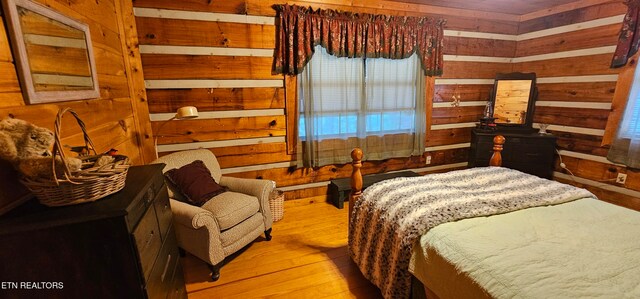 bedroom with light hardwood / wood-style floors and wood walls