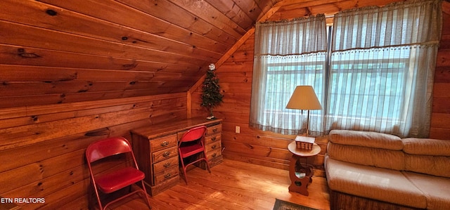 sitting room with light wood-type flooring, vaulted ceiling, wood walls, and wooden ceiling