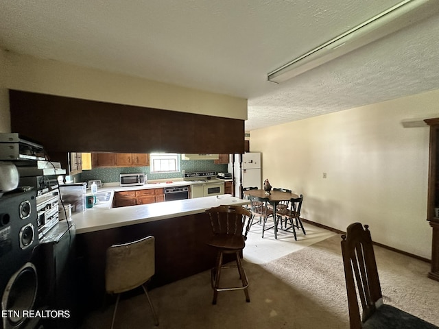 kitchen featuring light colored carpet, dishwasher, kitchen peninsula, double oven range, and a kitchen bar