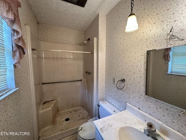 bathroom featuring a textured ceiling, toilet, walk in shower, and vanity