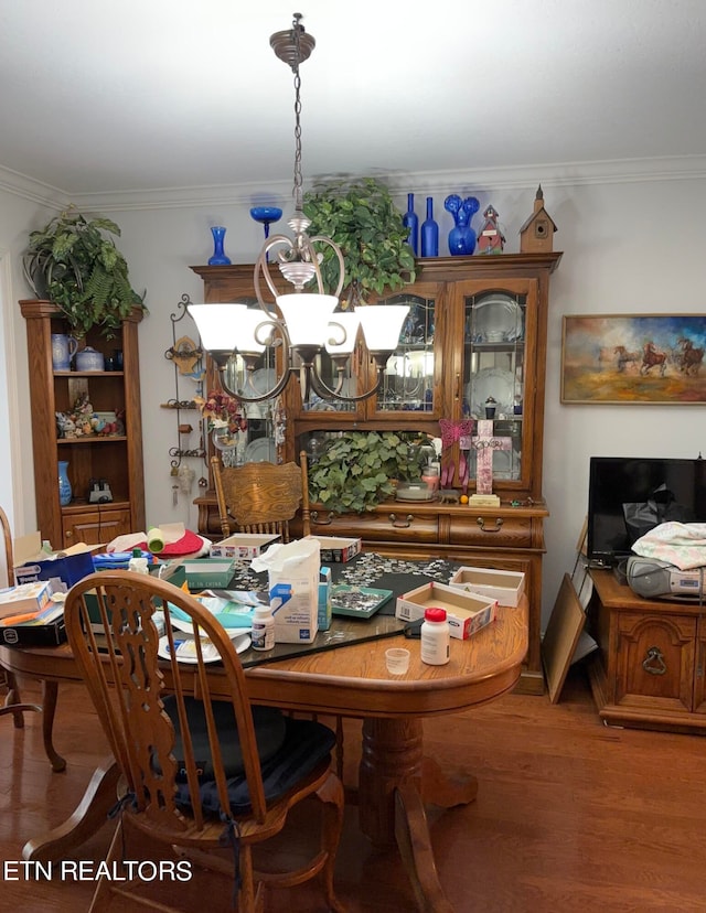 dining space with a notable chandelier, ornamental molding, and hardwood / wood-style floors