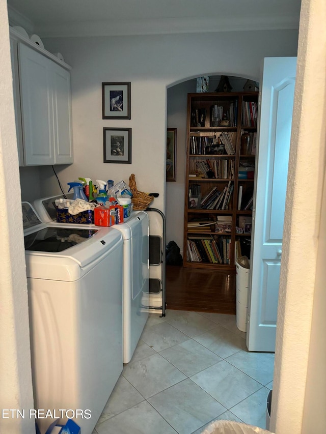 clothes washing area featuring cabinets, independent washer and dryer, and light tile patterned floors