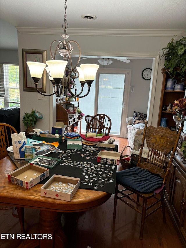 dining area featuring crown molding, hardwood / wood-style floors, and a chandelier