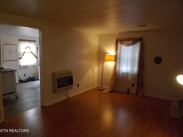 unfurnished living room featuring heating unit and hardwood / wood-style floors