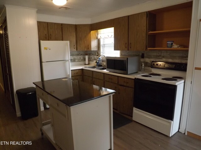 kitchen featuring white appliances, sink, backsplash, a kitchen island, and dark hardwood / wood-style flooring