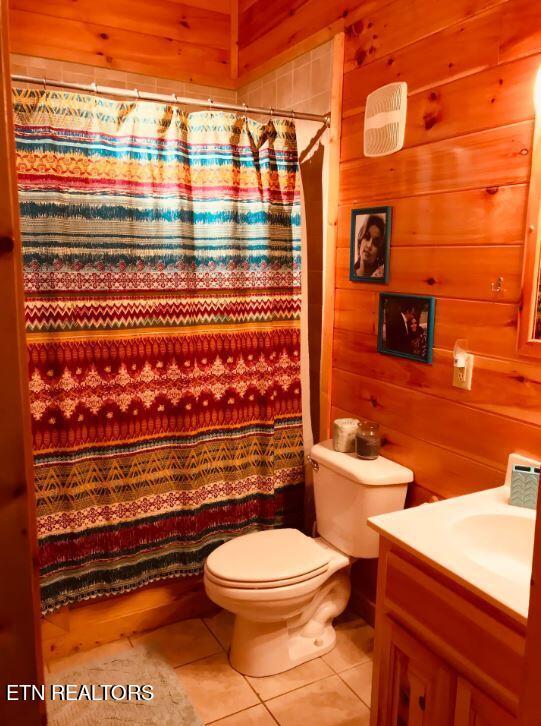 bathroom with curtained shower, wood walls, vanity, toilet, and tile patterned floors