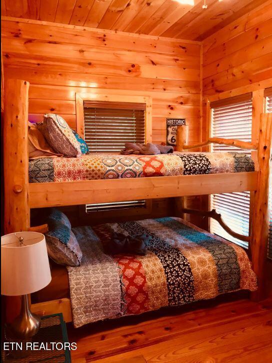 bedroom featuring multiple windows, hardwood / wood-style floors, wooden walls, and wooden ceiling