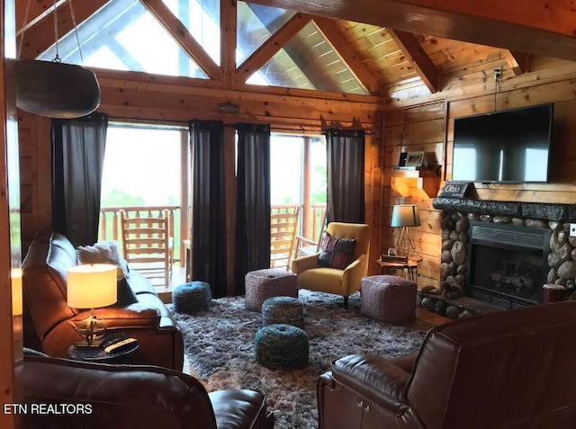 living room with a stone fireplace, wooden walls, lofted ceiling with beams, and plenty of natural light