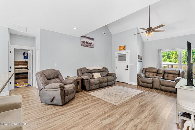 living room with high vaulted ceiling, ceiling fan, and light wood-type flooring