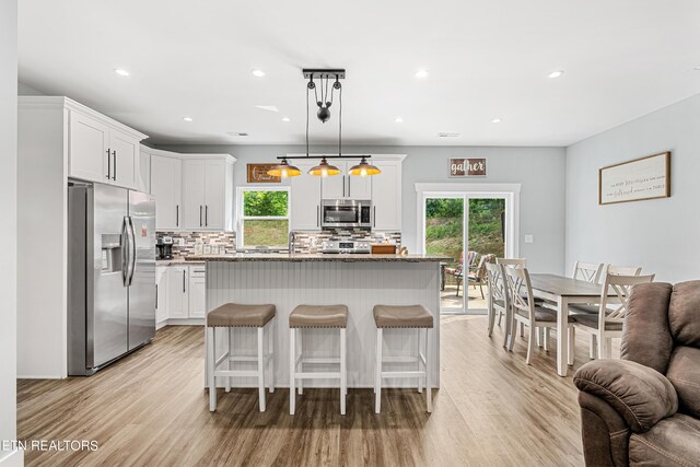 kitchen with hanging light fixtures, appliances with stainless steel finishes, a center island, and white cabinets