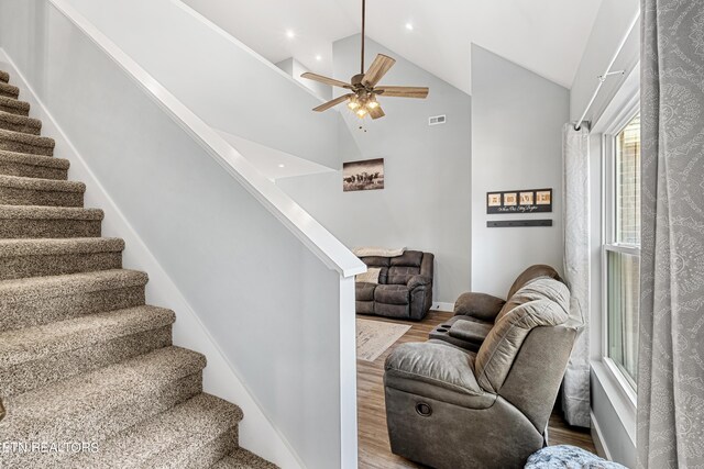 stairs featuring hardwood / wood-style flooring, high vaulted ceiling, and ceiling fan