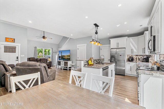 dining room featuring vaulted ceiling, ceiling fan, sink, and light hardwood / wood-style flooring