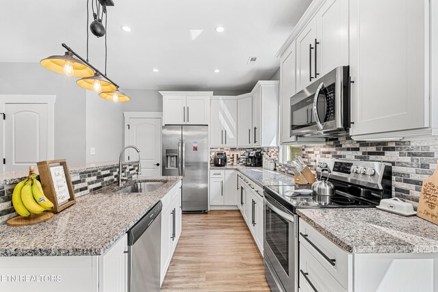 kitchen with white cabinetry, hanging light fixtures, stainless steel appliances, and light stone countertops