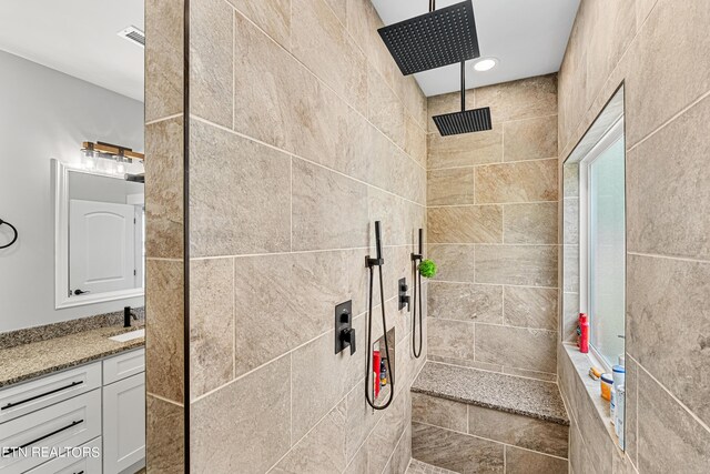 bathroom with vanity and tiled shower