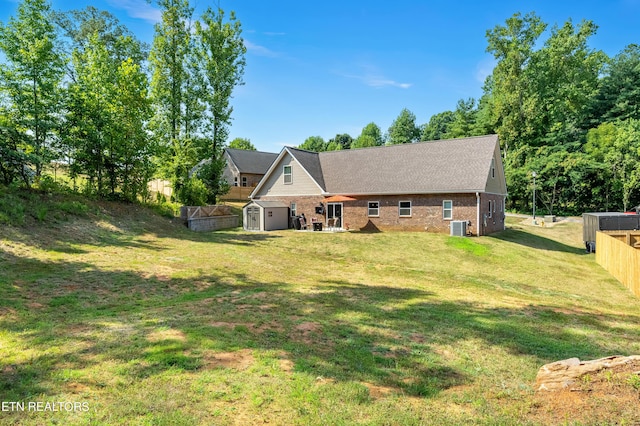 back of property with a yard, central AC unit, and a storage unit