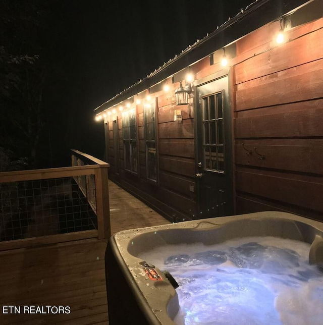 deck at night with a hot tub